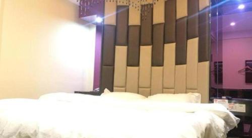 a bedroom with two beds and a large headboard at Shell Hotel Shanghai Baoshan Meilanhu Luosheng Road in Shanghai