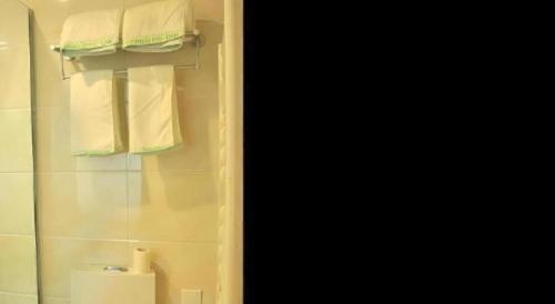 a bathroom with a shower with white towels at GreenTree Inn Liaocheng Donge Culture Street Express Hotel in Liaocheng