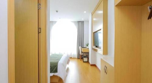 a bedroom with a bed and a bathroom with a mirror at GreenTree Inn Jiaxin Puyuan Kaixuan Road in Jiaxing