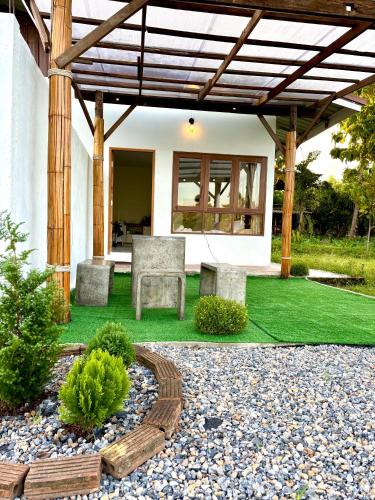 a patio with a bench under a wooden pergola at Baanfanglamoon in Ban Mae Mao