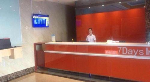 a man is standing behind a counter in a toll booth at 7 Days Inn Yining Xintiandi in Kipekyüzi