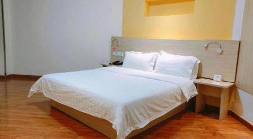 a bedroom with a large bed with white sheets and pillows at 7 Days Inn Yining Xintiandi in Kipekyüzi