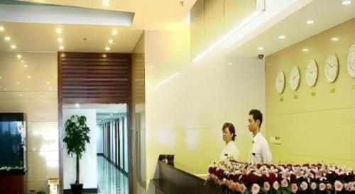 two people standing in a room with clocks on the wall at Shijia Inn On the Bund in Shanghai