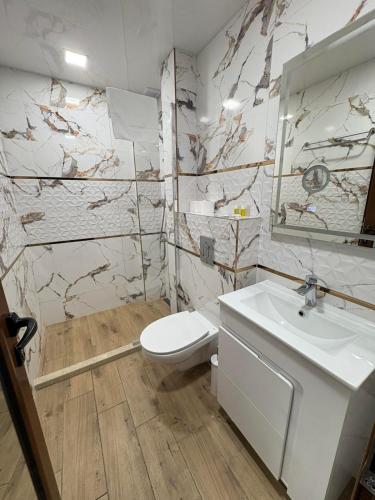 a bathroom with a white toilet and a sink at Hotel Fantazia in Haskovo