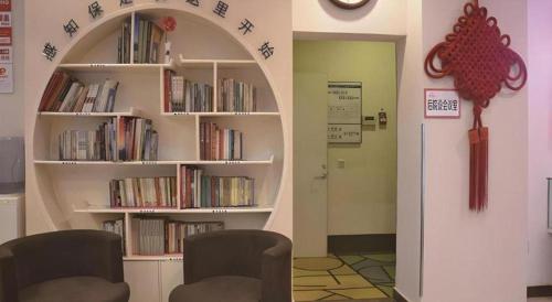 a room with two chairs and a book shelf with books at Shell Baoding Dongfeng Middle Road Kailian Hotel in Baoding