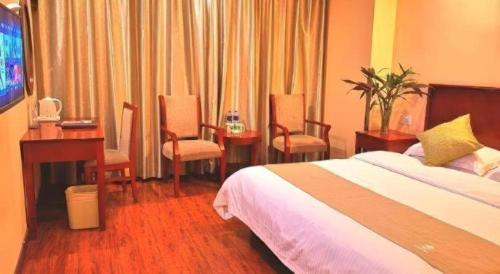 a hotel room with a bed and a desk and chairs at GreenTree Inn Yixing Zhangzhu Express Hotel in Xinchating