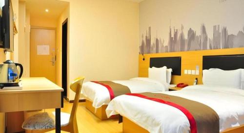 a hotel room with two beds and a desk at Thank Hotel Jiangxi Jiujiang Lianxi District Railway Station Square in Jiujiang