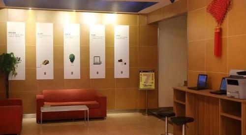 a waiting room with a couch and posters on the wall at 7 Days Inn Tianjin Binhai New District Yujiabao Metro Station in Binhai