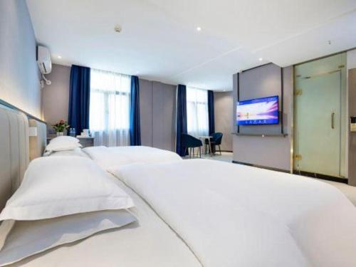 a bedroom with white beds and a flat screen tv at 7 Days Inn Luoyang Railway Station Wangcheng Avenue in Luoyang