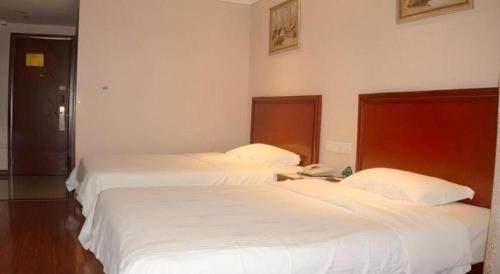 two beds in a hotel room with white sheets at GreenTree Inn Ganzhou Sankang Temple DaRunFa Express Hotel in Ganzhou