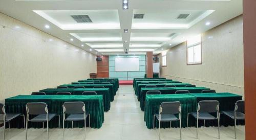 a room with green tables and chairs and a screen at GreenTree Inn Taiyuan PinGYAng Road Business Hotel in Taiyuan