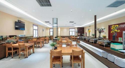 a restaurant with wooden tables and chairs in a room at GreenTree Inn Taiyuan PinGYAng Road Business Hotel in Taiyuan