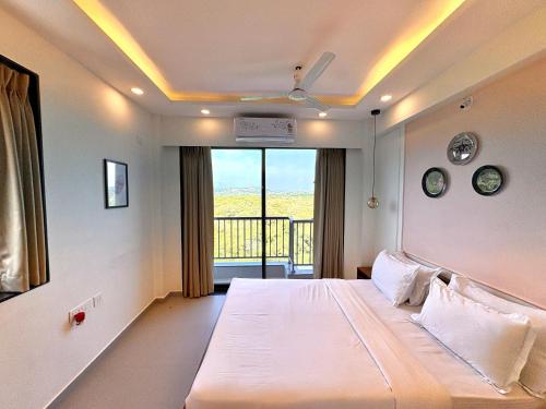 Un dormitorio con una cama grande y un balcón. en Vintage 2BHK Apartment - Gym, Pool & Amenities - Mangrove View, en Candolim