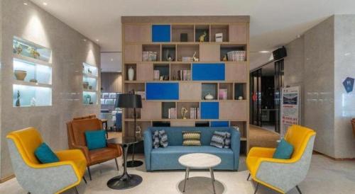 a living room with a blue couch and yellow chairs at Echarm Hotel Jinan Railway Station Daming Lake in Jinan