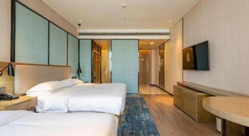 a hotel room with two beds and a flat screen tv at Echarm Hotel Jinan Railway Station Daming Lake in Jinan