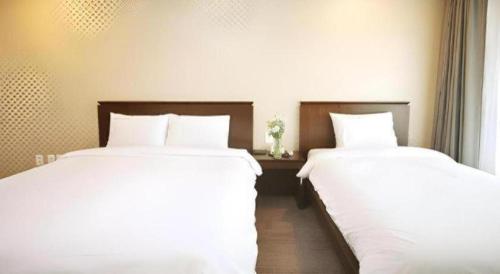 two beds sitting next to each other in a bedroom at Sea View Hotel in Jeju
