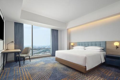 a bedroom with a large white bed and a desk at Four Points by Sheraton Bekasi in Bekasi