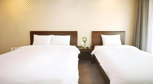 two beds sitting next to each other in a bedroom at Sea View Hotel in Jeju