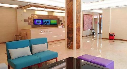 a waiting room with a blue couch and a tv at GreenTree Inn Qingyuan Qinghe Avenue Branch in Qingyuan