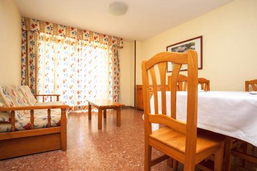 a bedroom with a bed and a chair and a window at Apartamentos Salou Centro in Salou