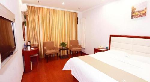a hotel room with a bed and a table and chairs at GreenTree Inn Yinchuan Pedestrian Street East Liqun Street Express Hotel in Yinchuan