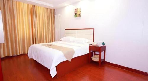 a bedroom with a bed and a table with a phone at GreenTree Inn Yinchuan Pedestrian Street East Liqun Street Express Hotel in Yinchuan
