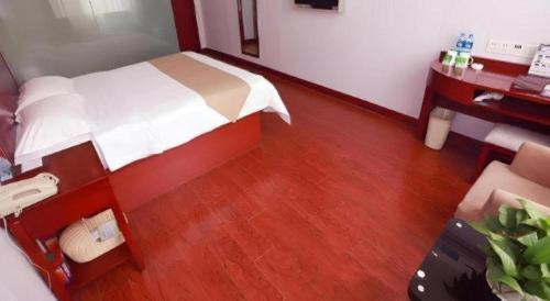 a bedroom with a bed and a wooden floor at GreenTree Inn Yinchuan Pedestrian Street East Liqun Street Express Hotel in Yinchuan