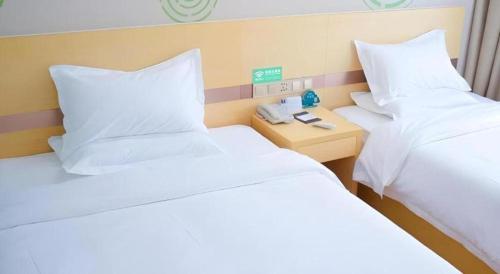 a hotel room with two beds with white pillows at GreenTree Inn Qufu High Speed Railway Station in Jining