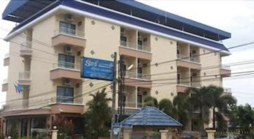 a large building with a blue sign in front of it at Ritzy House Hotel in Chumphon