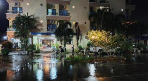 a building in the rain with trees and a building at Ritzy House Hotel in Chumphon