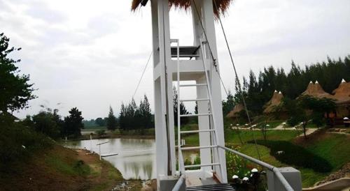 a white ladder sitting next to a body of water at Banrai Pornsawun in Ratchaburi