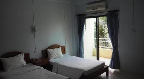 two beds in a hotel room with a window at Ritzy House Hotel in Chumphon