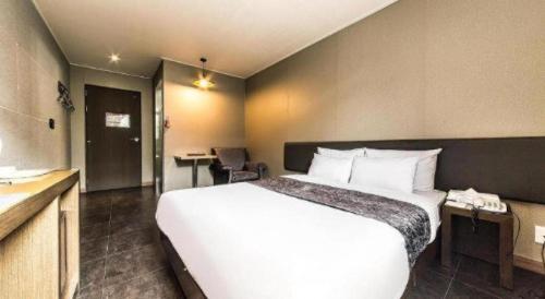 a hotel room with a large white bed and a kitchen at Line Plus Hotel in Gimpo