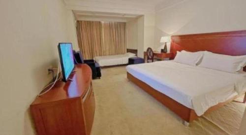 a hotel room with a bed and a flat screen tv at Changshu Jinling Tianming Grand Hotel in Suzhou