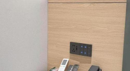 a electrical outlet on a wooden wall with remote controls at GreenTree Inn Jiangsu Xuzhou Jinshan Bridge Building Jinqiao Road Express Hotel in Xuzhou