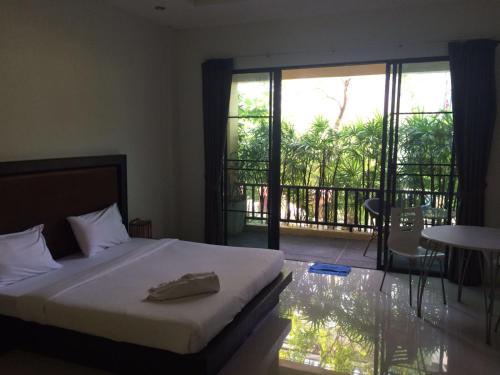 ein Schlafzimmer mit einem Bett und ein Balkon mit einem Tisch in der Unterkunft B Happy Resort - SHA ExtraPlus in Kamala Beach