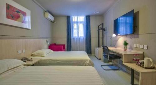 a hotel room with two beds and a desk at Jinjiang Inn Taizhou Huangyan Jiufeng Park in Daidong