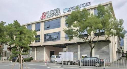 a large building with cars parked in front of it at Jinjiang Inn Taizhou Huangyan Jiufeng Park in Daidong