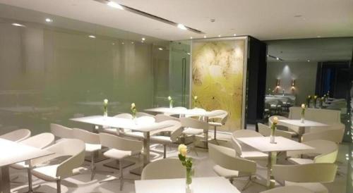 a restaurant with white tables and white chairs at Jinjiang Inn Taizhou Huangyan Jiufeng Park in Daidong