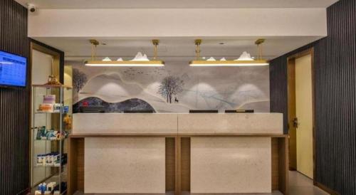 a lobby with a counter with a painting on the wall at Jinjiang Inn Taizhou Huangyan Jiufeng Park in Daidong