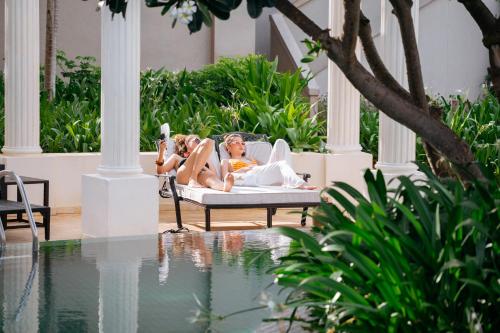 two women laying on a bed next to a swimming pool at The IMPERIAL Vung Tau Hotel in Vung Tau