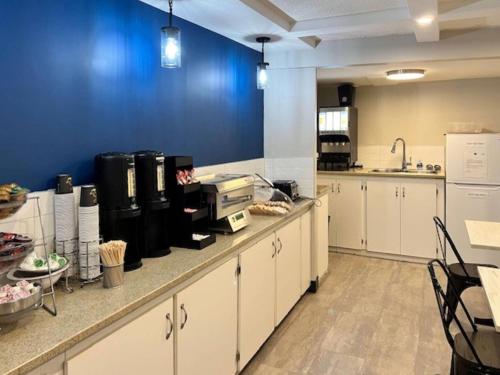 a large kitchen with white cabinets and a blue wall at Econo Lodge Motel Village in Calgary