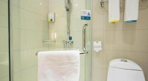 a bathroom with a shower with a toilet and a towel at City Comfort Inn Wuhan High Speed Railway Station in Wuhan