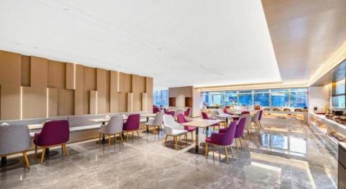 a restaurant with purple chairs and tables and windows at City Comfort Inn Wuhan High Speed Railway Station in Wuhan