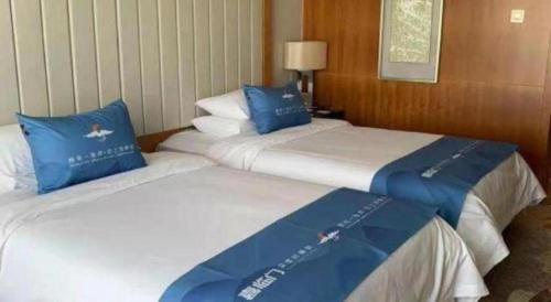 two beds in a hotel room with blue pillows at Ramada Plaza by Wyndham Yangzhou Casa in Yangzhou