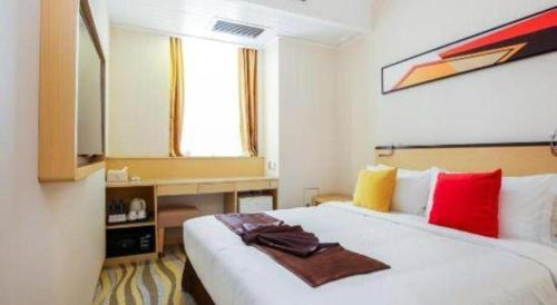 a bedroom with a large white bed with red and yellow pillows at Cozy Hotel Xiamen in Xiamen