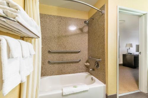a bathroom with a tub and a shower with towels at Sleep Inn & Suites Ruston Near University in Ruston
