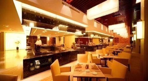 a restaurant with yellow chairs and tables and a kitchen at Ramada Plaza by Wyndham Yangzhou Casa in Yangzhou