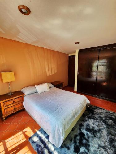 a bedroom with a bed and a lamp and a table at Room with Parking near the Center in Guanajuato