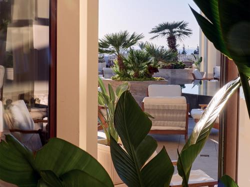 a balcony with a view of a patio with palm trees at Grecotel LUXME Kos in Kos Town
